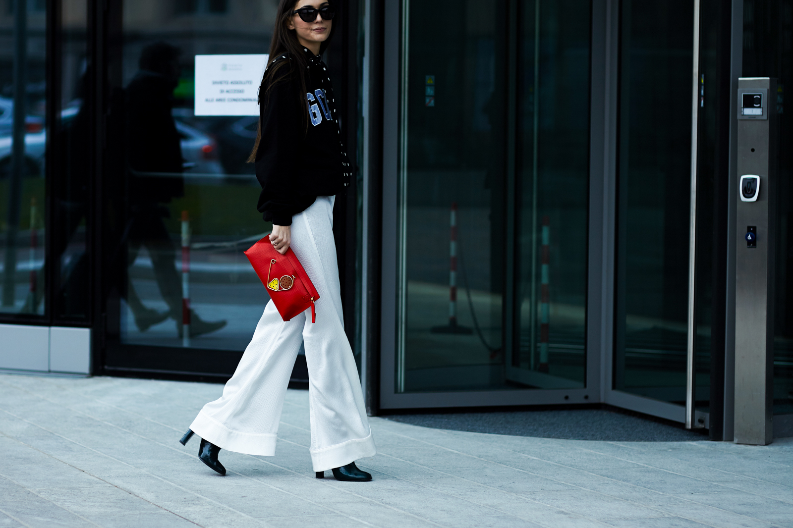 MFW Street Style: Italian stylist Diletta Bonaiuti wearing a black GCDS sweatshirt, polka dot scarf and red Loewe clutch bag after a fashion show in Milan