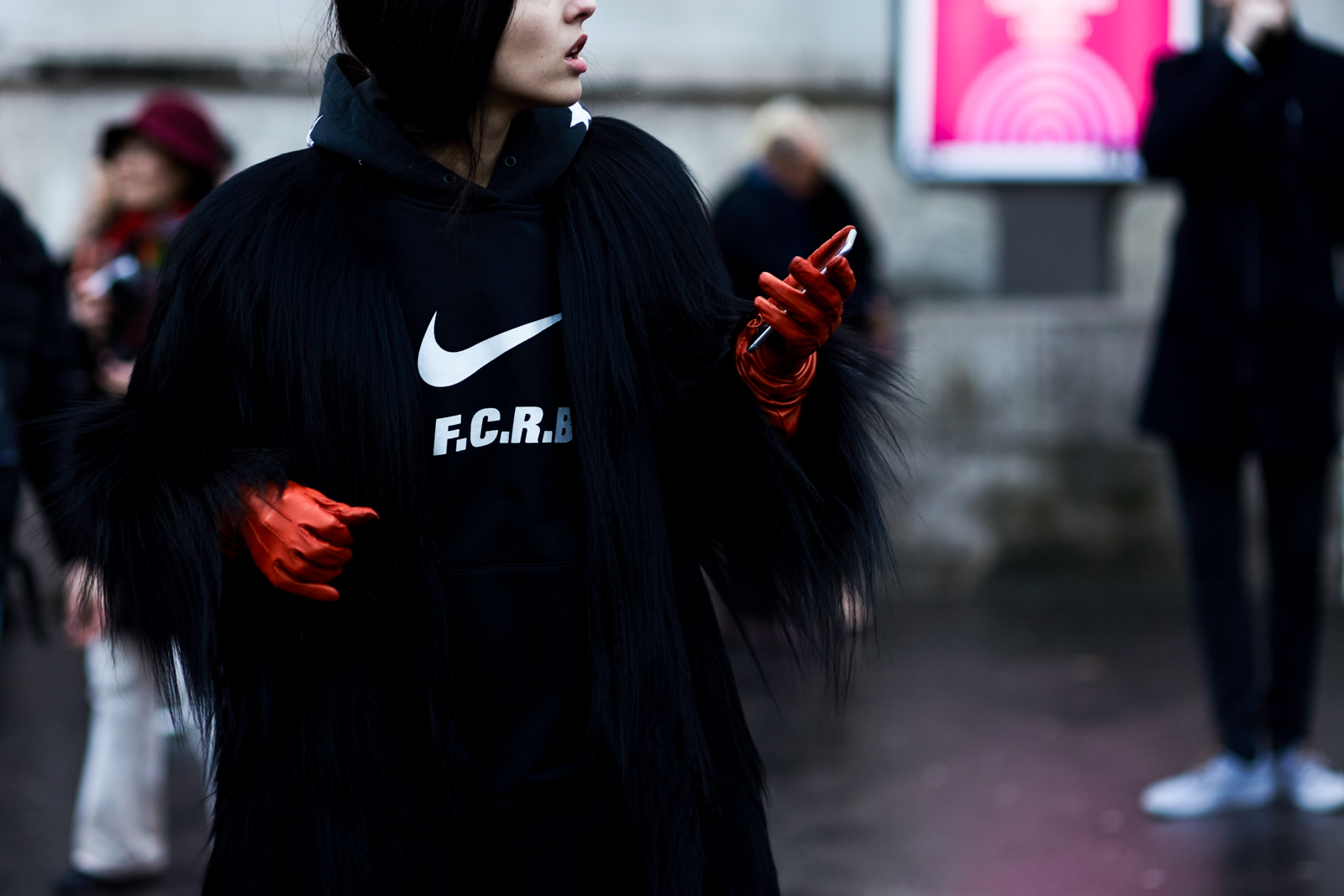 Street Style Gilda Ambrosio wearing a Nike hoodie, black fur coat and red leather gloves at the Rochas Fall/Winter 2016-2017 fashion show in Paris, France