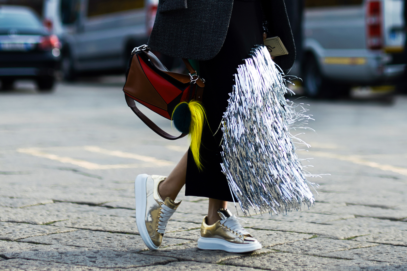MFW Street Style: A woman wearing a fringed loewe skirt, Loewe bag and Alexander McQueen metallic sneakers before the Gucci Fall 2016 fashion show in Milan