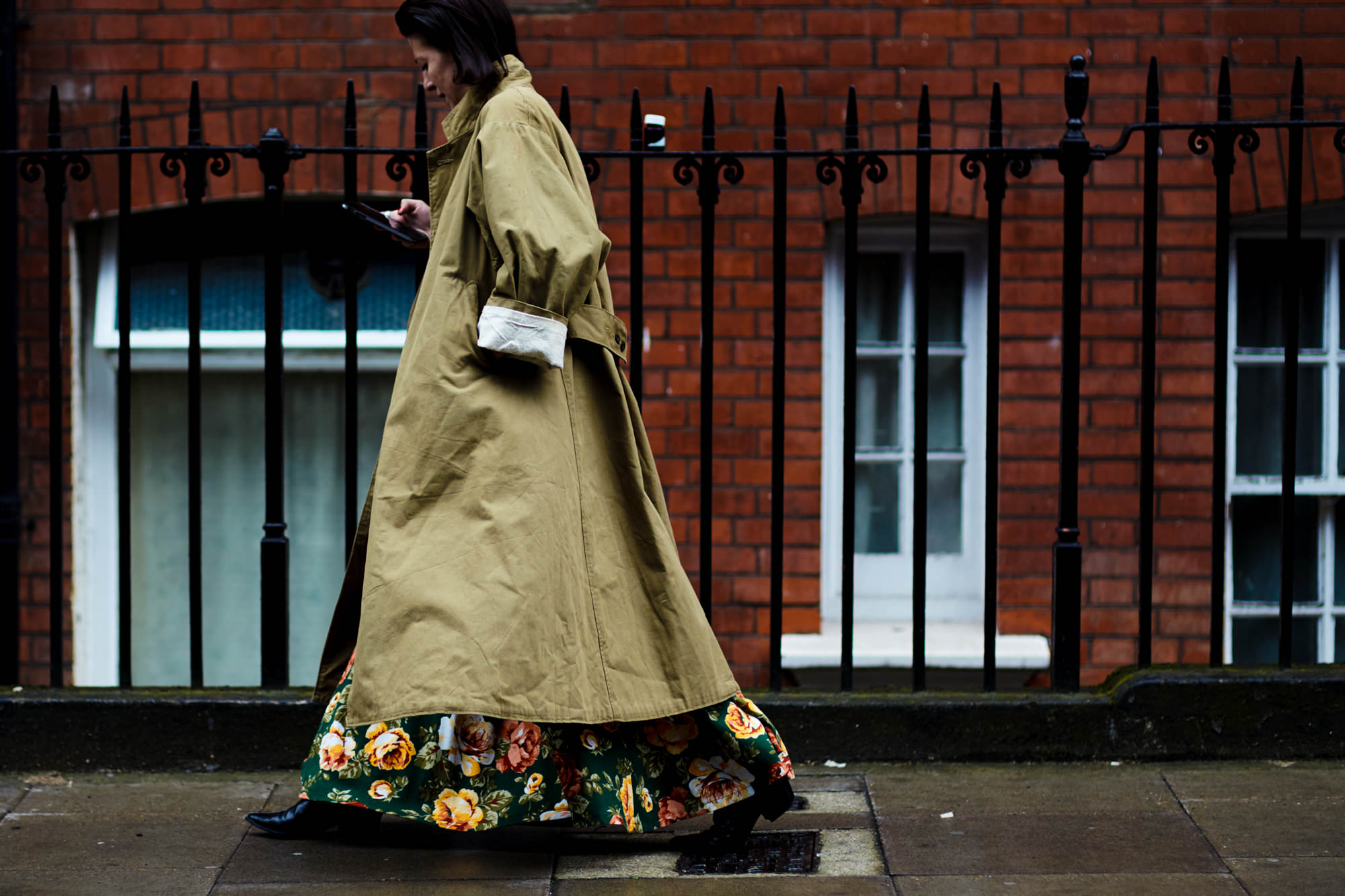 Woman wearing long floral dress and long trench coat after the J.W.Anderson Men's fashion show in London, UK